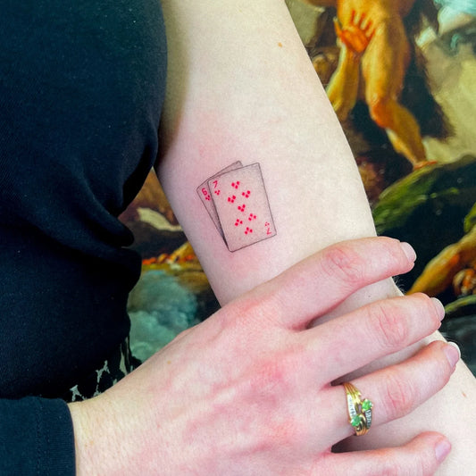 micro realism red poker cards minimalist tattoo on woman bicep