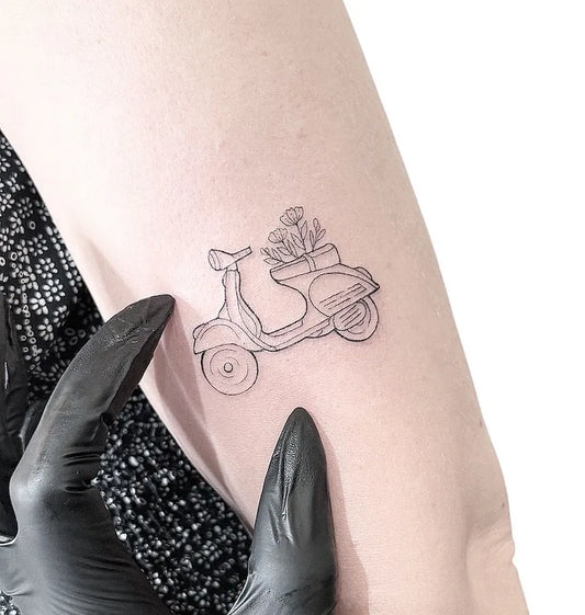 motorcycle with flowers fine line outline tattoo on woman upper arm