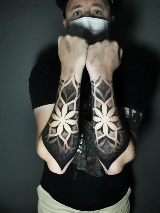 matching blackwork geometric tattoo on man forearm