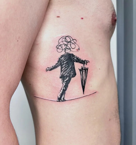abstract headless man in suit with umbrella walking on wire tattoo on man rib