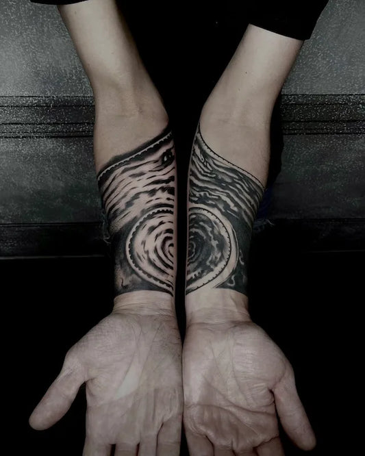 matching blackwork abstract brush stroke tattoo on man forearm