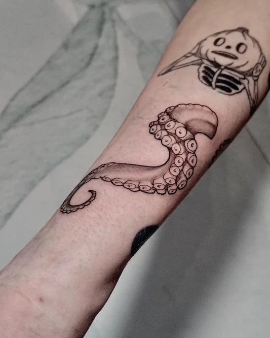 black and grey tattoo of an octopus tentacle on forearm