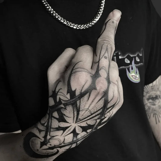 blackwork tattoo on hand and middle finger