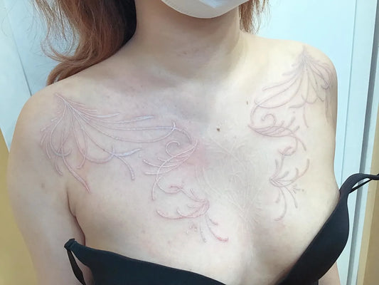 floral fine line white ink tattoo on woman chest and shoulder