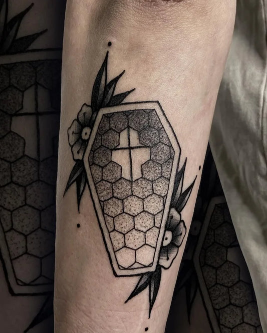 traditional hexagonal coffin tattoo with floral elements on forearm