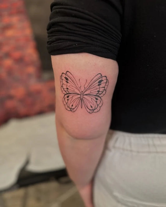 abstract butterfly outline fine line tattoo on woman upper arm back