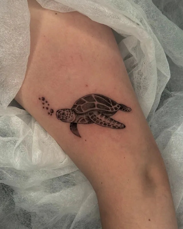 black and grey sea turtle with bubbles dotwork tattoo on women upper arm