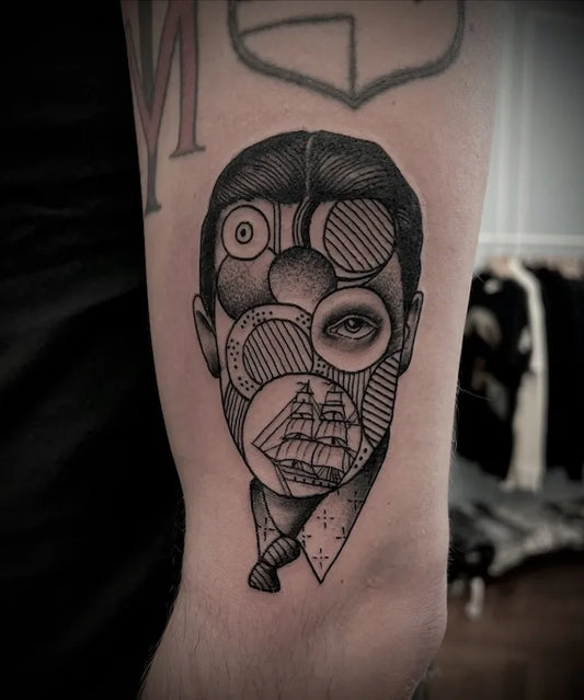 abstract geometric one eye man black and grey tattoo on upper arm