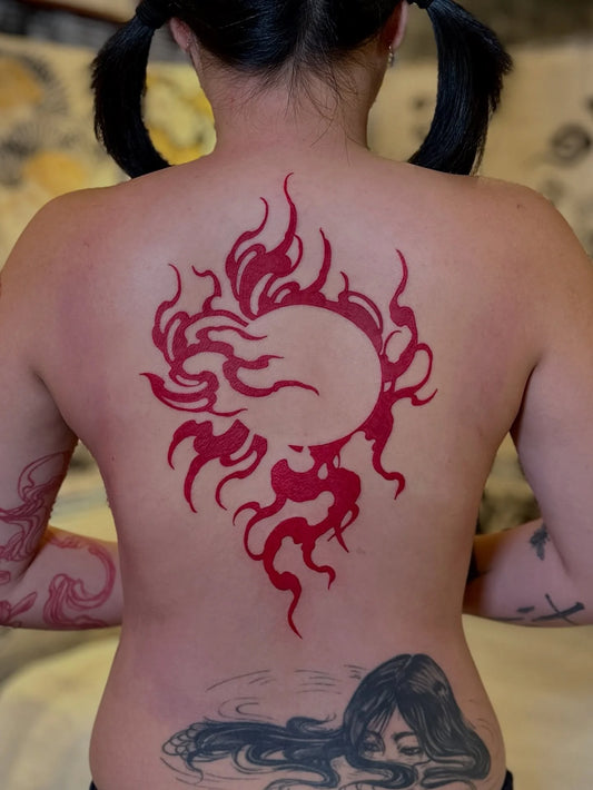 red blackwork tribal sun tattoo on woman back