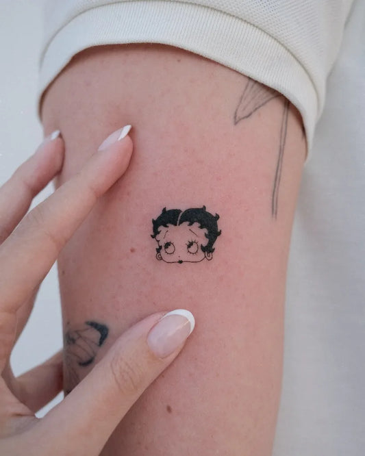 minimalist betty boop fine line tattoo on upper arm