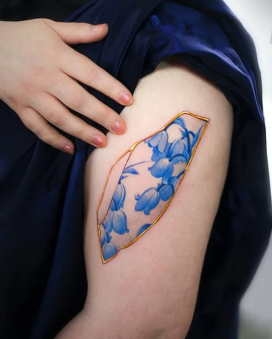 blue gold ceramic porcelain floral color realism tattoo on woman upper arm