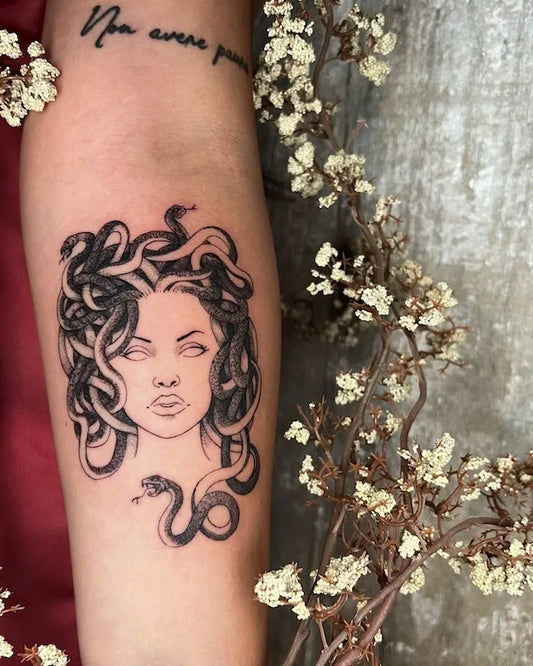 black and grey medusa tattoo on woman inner forearm