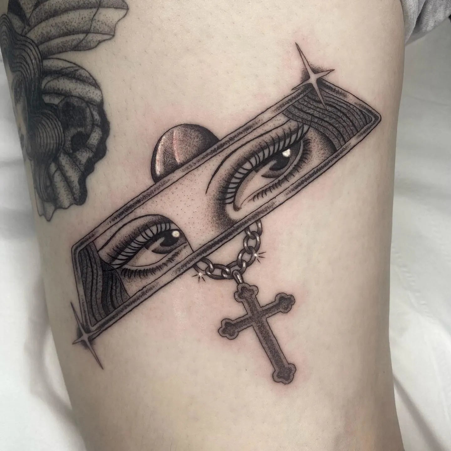 chicano style tattoo of a pair of woman eyes with a cross pendant