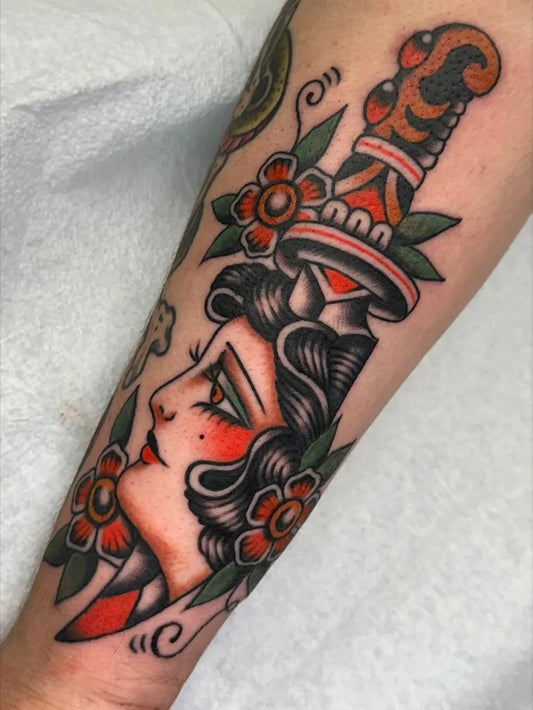 Big American Traditional Dagger with Pinup Girl and Flowers on Women Arm Tattoo by @charlie.rufino
