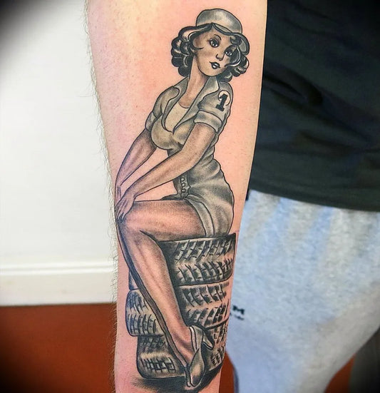 Big American Traditional Pin Up Girl Sitting on Tire Tattoo on Men Arm by @inkaddictiontattoodoncaster