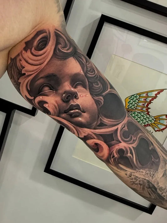 Big Black and Grey Cherub with Floral Ornaments and Butterfly Tattoo on Men Arm by @ray_ink_inc
