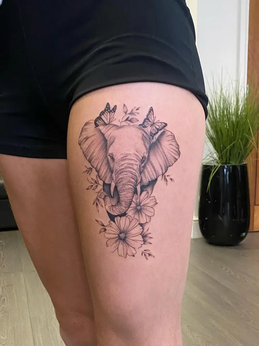 Big Black and Grey Elephant with Flowers and Butterflies Tattoo on Women Thigh by @inkerella_tattoo