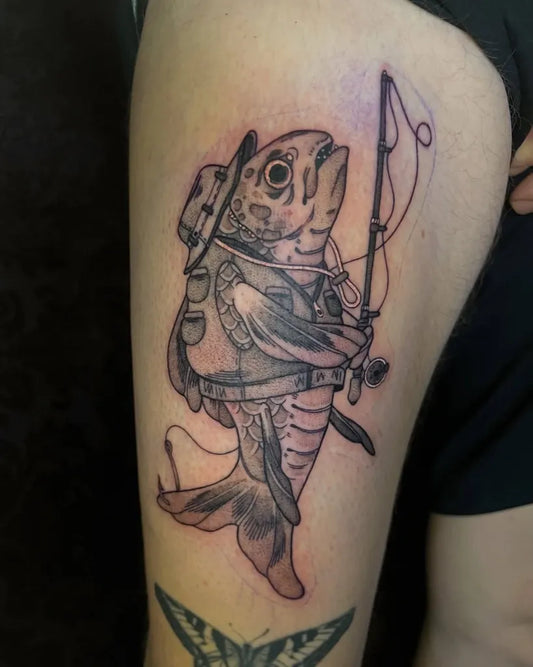 Big Black and Grey Fish with Hat and Fishing Rod Tattoo on Men Thigh by @jaime.dick