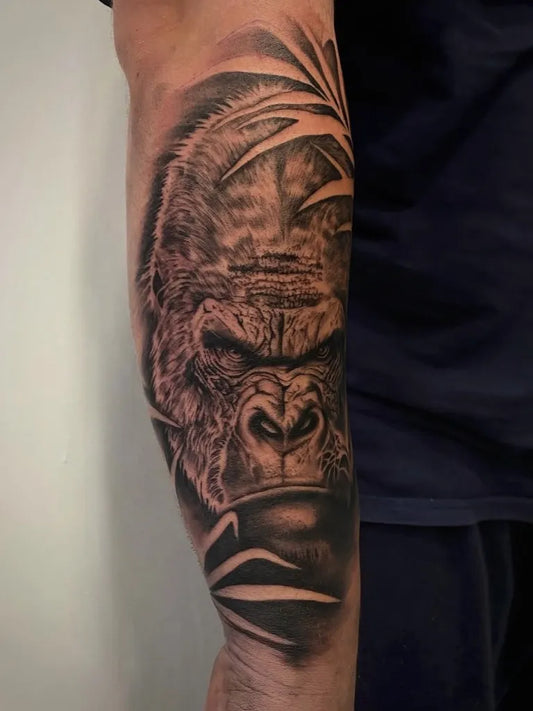Big Black and Grey Gorilla and Palm Leaves Tattoo on Men Arm by @7sinsstevenagetattoo