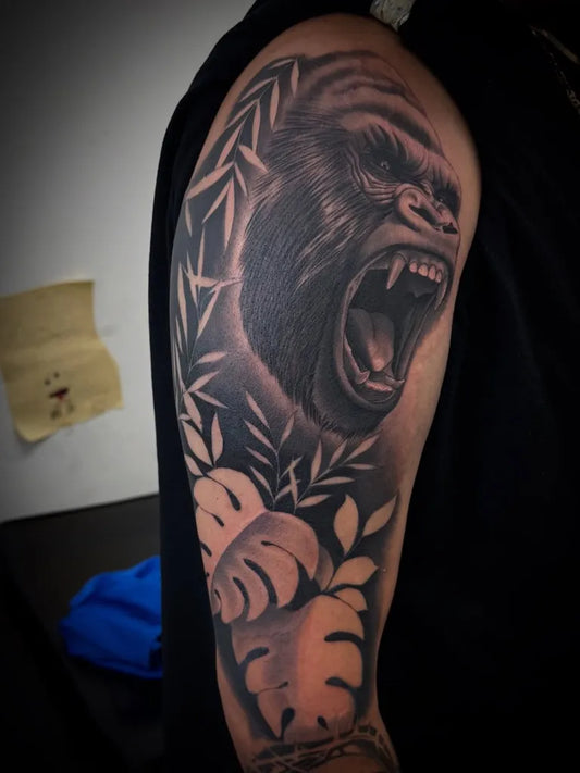 Big Black and Grey Gorilla with Bamboo and Monstera Leaves Tattoo on Men Shoulder by @guzman_tattoos_
