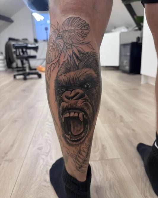 Big Black and Grey Gorilla with Leaves Tattoo on Men Leg by @kateestudio