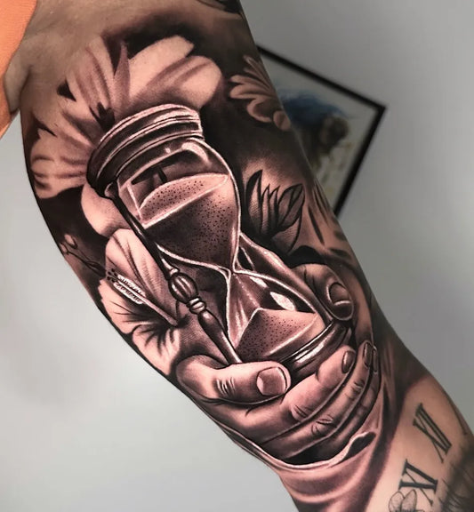Big Black and Grey Hourglass with Flowers and Hands Tattoo on Men Arm by @cortes_tattoo