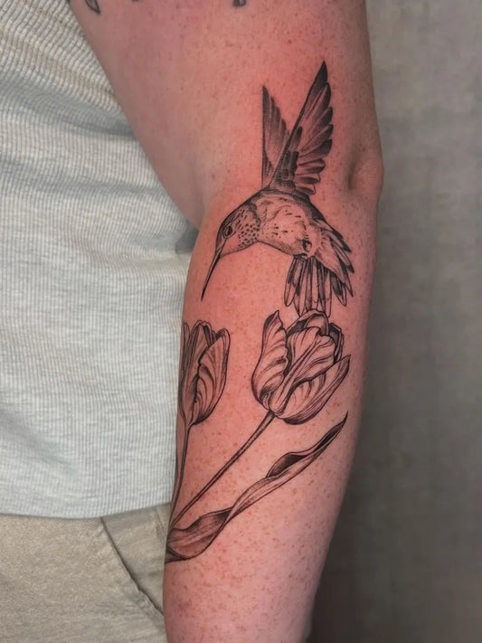 Big Black and Grey Hummingbird and Tulips on Women Arm Tattoo by @zoeloutattoo