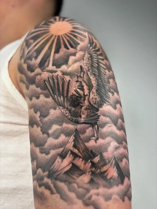 Big Black and Grey Icarus with Sun and Mountains on Men Shoulder Tattoo by @mitchelkelftattoo