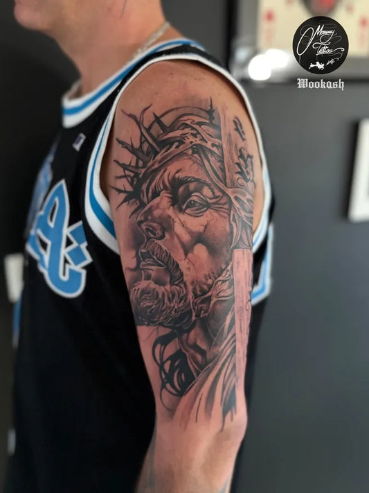 Big Black and Grey Jesus with Crown of Thorns Tattoo on Men Arm by @mommytattoo.studio