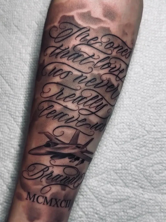 Big Black and Grey Jet Fighter Script and Roman Numerals Military Tattoo on Men Arm by @yoebrandon.tattoos