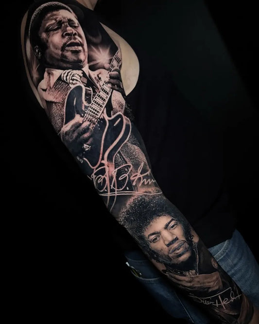 Big Black and Grey Jimi Hendrix Portrait and Guitar Music Tattoo on Men Arm by @joegregorytattoos