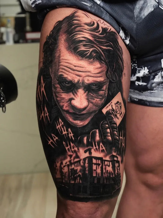 Big Black and Grey Joker Portrait and Cityscape on Men Thigh Tattoo by @tattoosbycodygibbs