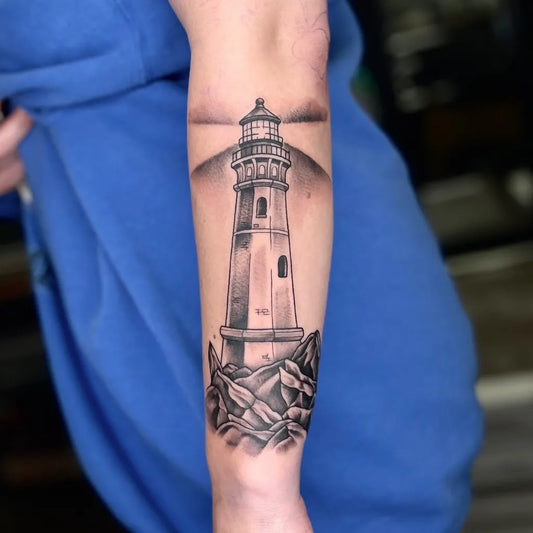 Big Black and Grey Lighthouse with Rocks Tattoo on Men Arm by @ldempseytattoos