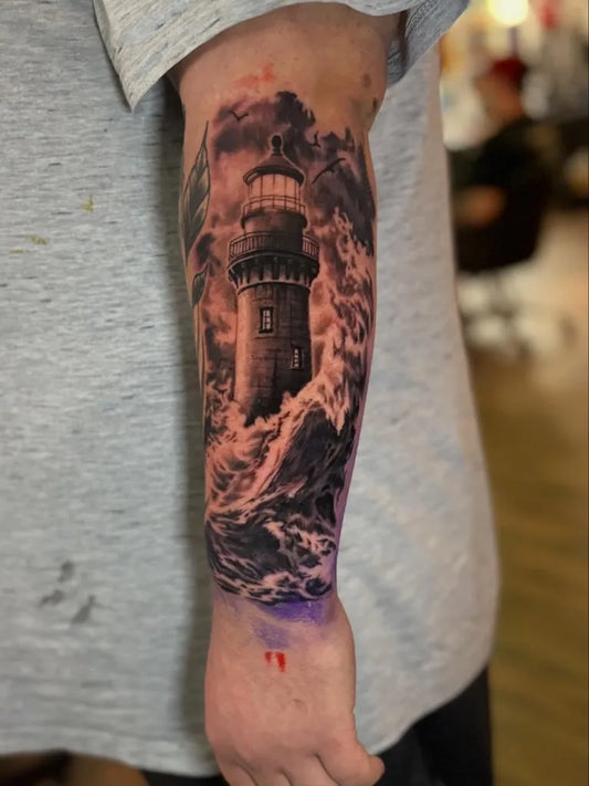 Big Black and Grey Lighthouse with Stormy Waves Tattoo on Men Arm by @tattoobird_official