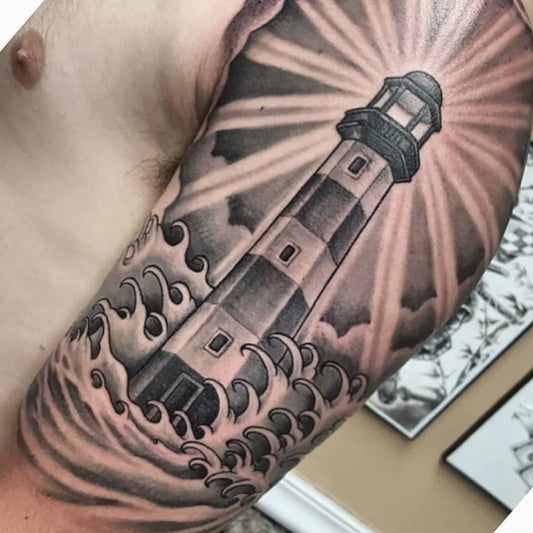 Big Black and Grey Lighthouse with Waves and Rays Tattoo on Men Arm by @davincitattoostudio