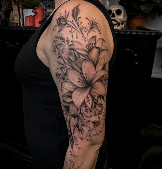 Big Black and Grey Lily Flowers Tattoo on Women Upper Arm by @gabriellatattoo