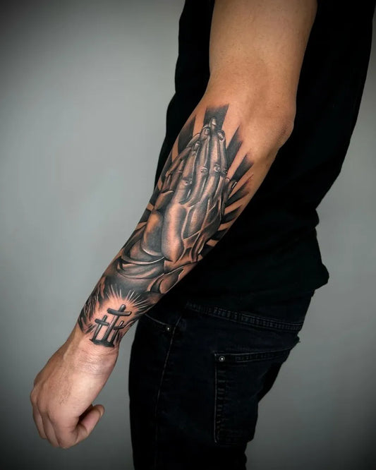 Big Black and Grey Praying Hands with Cross and Rays Tattoo on Men Arm by @jhonnye_tattoo