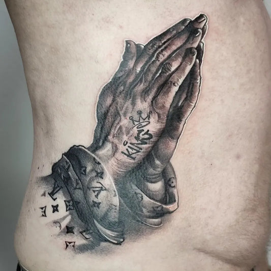 Big Black and Grey Praying Hands with Crown and Rosary Tattoo on Men Rib by @piotrek_taton_tattoo