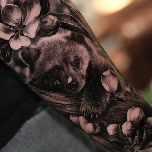Big Black and Grey Raccoon and Flowers Animal Tattoo on Men Arm by @kiyoharu_tattooer