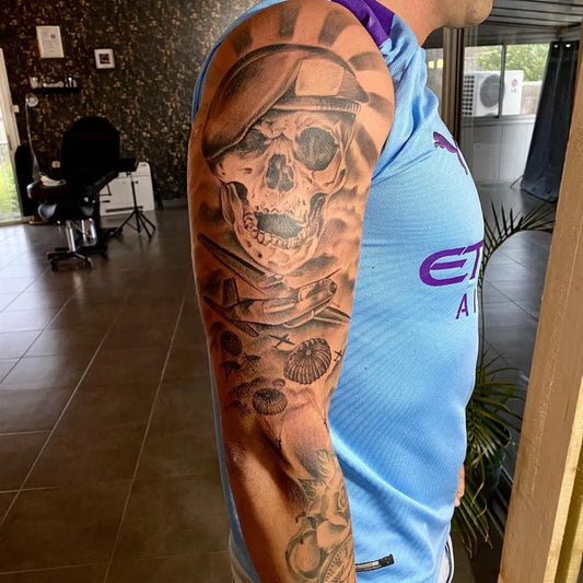 Big Black and Grey Skull and Sunburst Military Tattoo on Men Arm by @jerome.schlichting