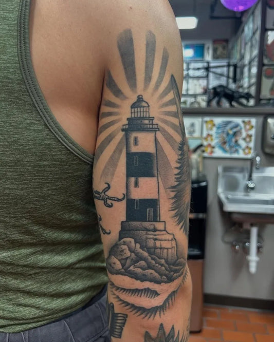 Big Blackwork Lighthouse with Rays and Rocks Tattoo on Men Arm by @redgrizzly123