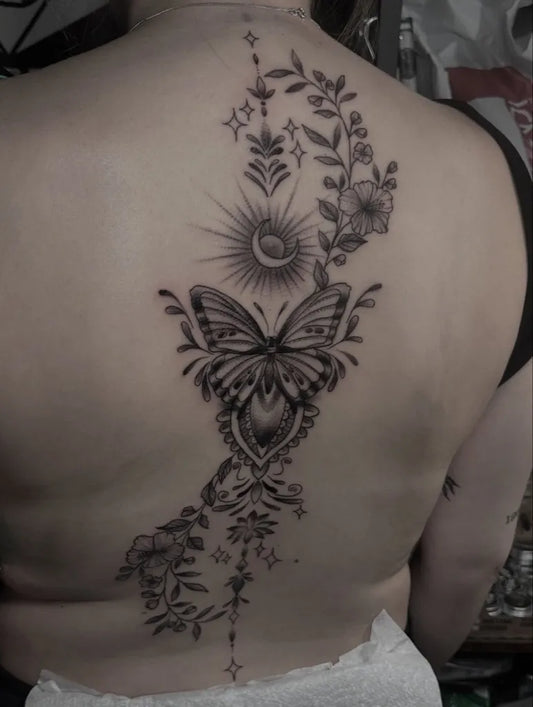 Big Botanical Butterfly and Sun on Women Spine Tattoo by @antclaytattoo