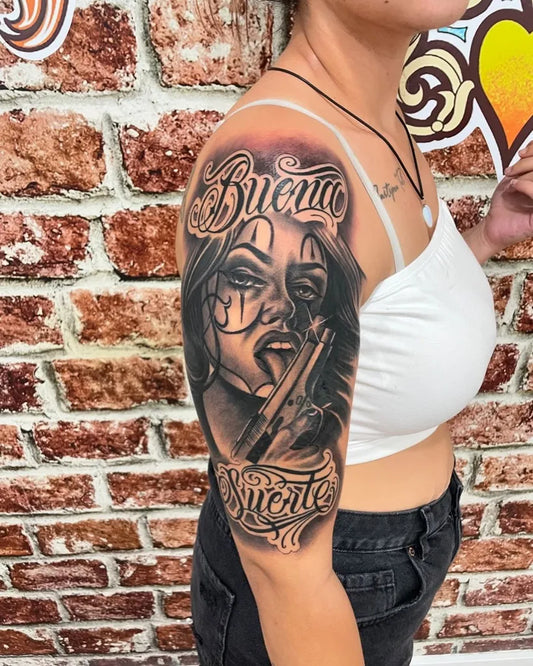 Big Chicano Woman with Gun and Buena Gente Script Tattoo on Women Arm by @almapuratattoo