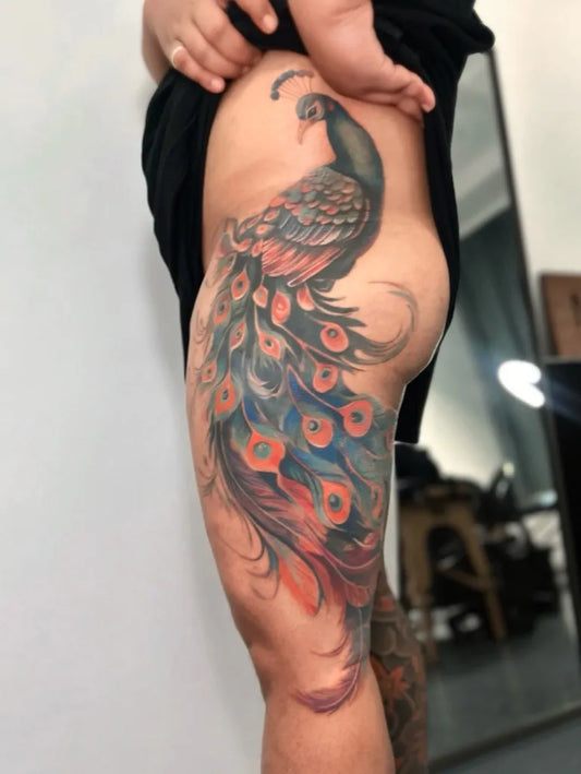 Big Colorful Peacock on Women Thigh Tattoo by @angelyn.tattoo