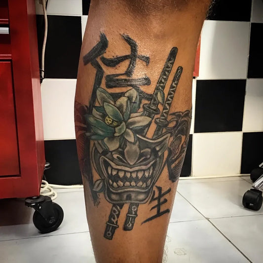Big Japanese Oni Mask Lotus Swords on Men Leg Tattoo by @dragonfly_tattoo_corfu