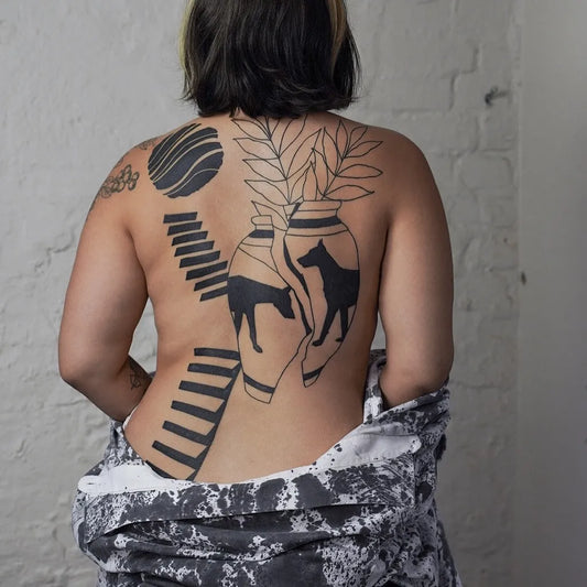 Big Minimalist Vase Dog Steps on Women Back Tattoo by @studio4.no