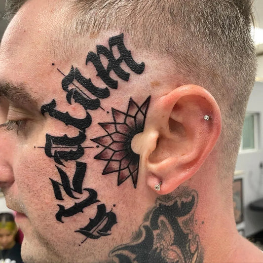 Big Old English lettering and mandala on Men Face Tattoo by @tristintattoos