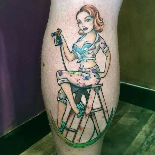 Big Pin Up Girl Painting on a Ladder Tattoo on Women Leg by @rawhidetattoostudio