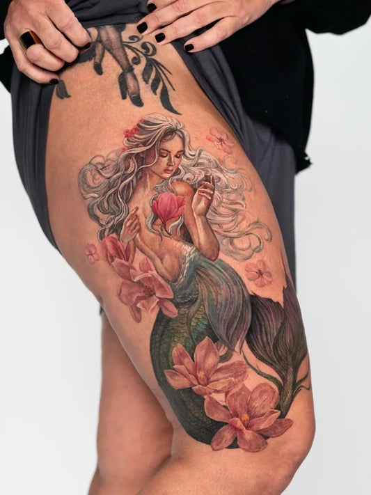 Big Realism Mermaid with Heart and Flowers Tattoo on Women Thigh by @sogdiana.sk