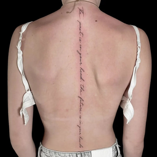 Big Script Text on Women Spine Tattoo by @dna.ink.sliedrecht